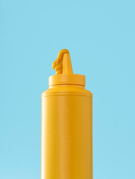 Mustard plastic bottle isolated on a blue background