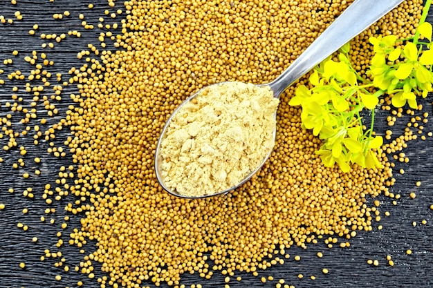 Mustard powder in spoon with flower on board top