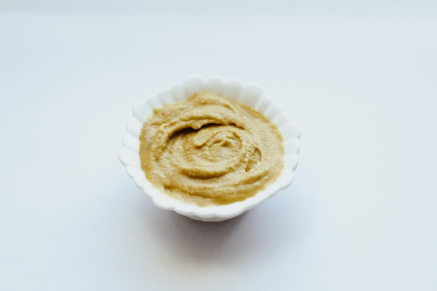 Mustard sauce in a white bowl on a white table