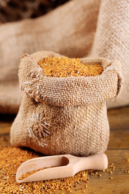 Mustard seeds in bag on wooden background