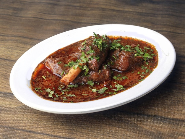 Photo mutton curry or lamb curry spicy and delicious dish served over a rustic wooden background selective focus