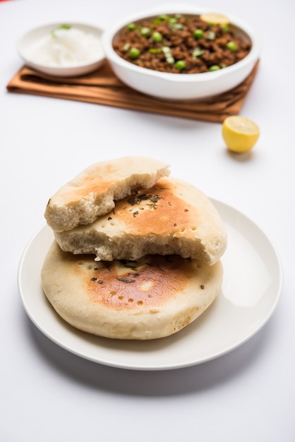 Montone kheema pav o carne macinata piccante indiana servita con pane o kulcha, guarnita con piselli. sfondo lunatico. messa a fuoco selettiva