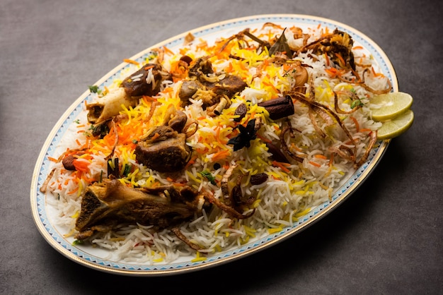 Mutton or lamb biriyani with basmati rice, served in a bowl over moody background.