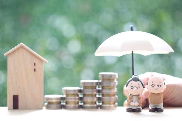 Mutual fundLove couple senior and hand holding the umbrella with stack of coins money on natural green background Save money for prepare in future and pension retirement concept