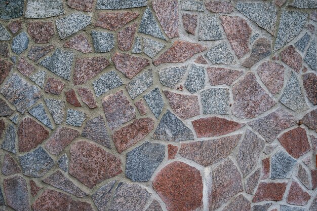 Muur van rode en grijze granieten stenen vastgemaakt met cement