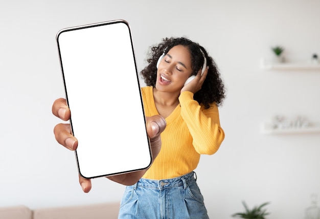 Muziek-app Jonge zwarte vrouw met grote lege smartphone en zingen