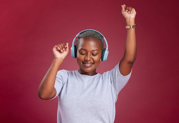 Muziek dans en vrijheid met een zwarte vrouw in de studio op een rode achtergrond om te dansen of plezier Danser koptelefoon en zorgeloos met een jonge vrouw streaming audio met een online service om van te genieten