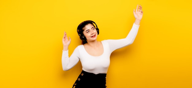 Muziek en ontspanning Aziatische vrouw die een telefoon gebruikt om naar muziek te luisteren Aziatische vrouw die een smartphone gebruikt op een gele achtergrond met vrije ruimte