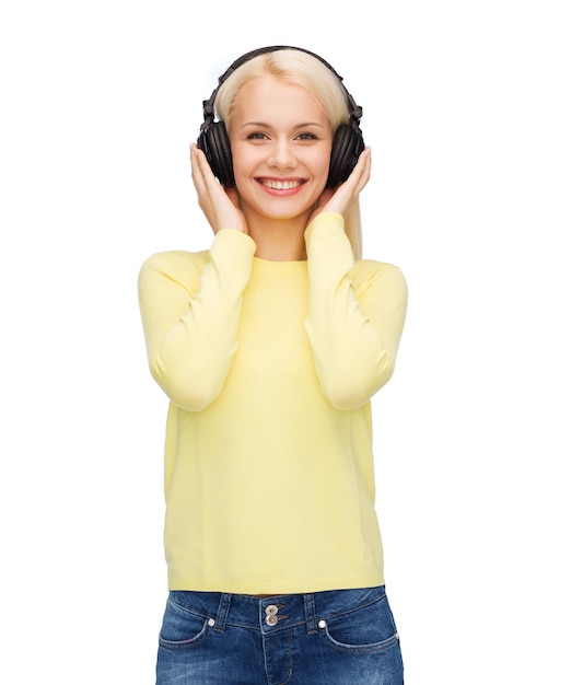 muziek- en technologieconcept - glimlachende jonge vrouw die naar muziek luistert met een koptelefoon