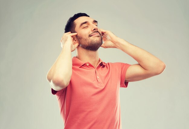 Foto muziek, gebaar en mensenconcept - gelukkige glimlachende man die naar muziek luistert met denkbeeldige koptelefoon over grijze achtergrond