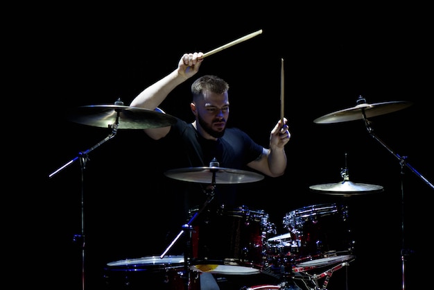 Muziek, mensen, muziekinstrumenten en vermaakconcept - mannelijke musicus die met drumsticks trommels en cimbalen spelen bij overleg of studio