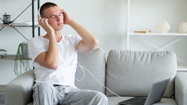 Muziek ontspannen Geïnspireerde man Stereogeluid Rustige casual man die favoriete melodie luistert in koptelefoon die is aangesloten op een laptop die op de bank zit in een licht kamerinterieur