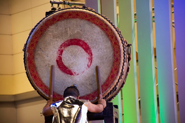 Muziekband en thaise mannen actrice of muzikant spelen klassiek instrument grote gong-trommel en dansen op het ritme voor showbezoeker gast op podiumtheater in tentoonstellingshal in Bangkok, Thailand