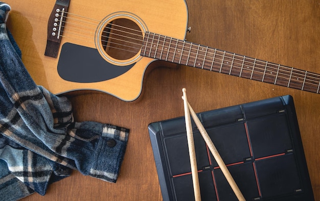 Muziekcompositie met akoestische gitaar en drumsticks bovenaanzicht