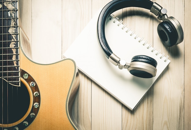 Foto muziekhoofdtelefoon met gitaar op houten tablet.