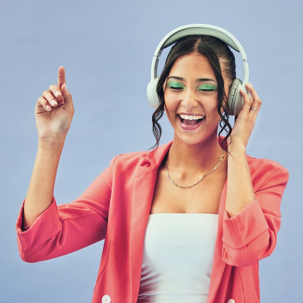 Muziekhoofdtelefoons en gelukkige vrouw dansen in studio met podcasttrack of audio-abonnement op blauwe achtergrond Gezichtsglimlach en damemodel met vrijheidsenergie of verhuizen naar radio of feel good podcast