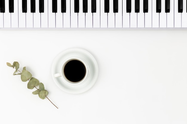 Muzikaal toetsenbord en een kopje koffie op een witte achtergrond plat leggen ruimte voor tekst