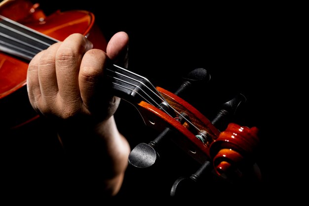 Muzikant die viool speelt Een violist of violist die met een zwarte achtergrond optreedt