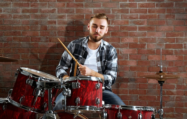 Muzikant drummen op bakstenen muur achtergrond