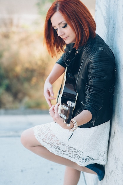 Muzikant jonge vrouw met rood haar met een akoestische gitaar