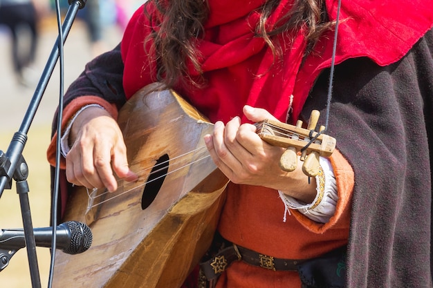 Muzikant voert een deuntje uit op een middeleeuws muzikaal tokkelinstrument dat lijkt op een mandoline of luit_