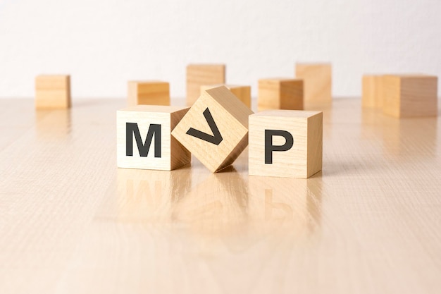 MVP an abbreviation of wooden blocks with letters on a gray background reflection caption on the mirrored surface of the table selective focus