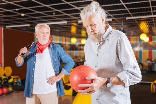 My favourite game. Nice aged man looking at the bowling ball while holding it in their hand