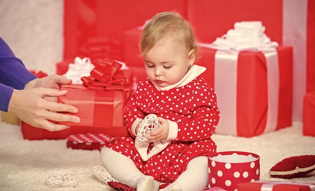 My first christmas sharing joy of baby first christmas with\
family baby first christmas once in lifetime event little baby play\
near pile of wrapped red gift boxes gifts for child first\
christmas