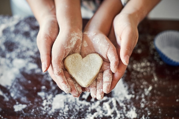 Foto il mio cuore tiene il mio cuore inquadratura ritagliata di una ragazza irriconoscibile e sua madre con in mano un biscotto a forma di cuore in cucina a casa