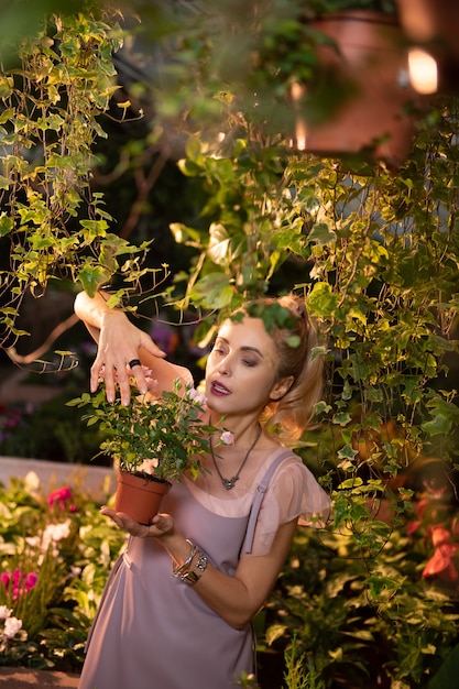 My hobby. Nice attractive woman taking care of flowers while standing in the garden