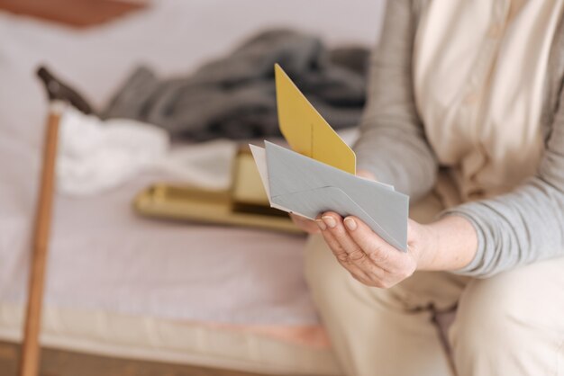 Foto la mia posta. primo piano di buste tenuto da una bella donna invecchiata piacevole mentre era seduto sul letto