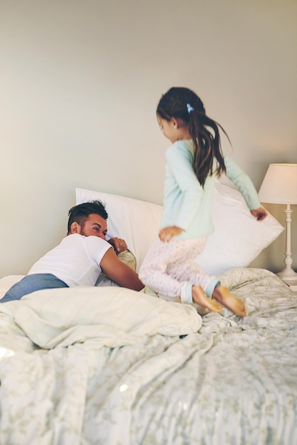 My turn to tickle you back Shot of a cheerful little girl jumping on the bed to wakeup her sleeping dad at home