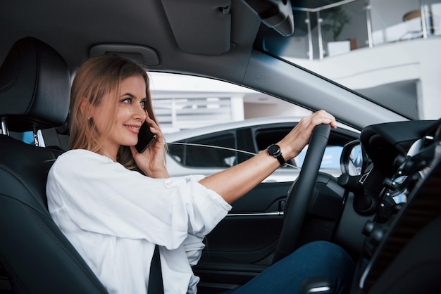 Photo on my way beautiful blonde girl sitting in the new car with modern black interior