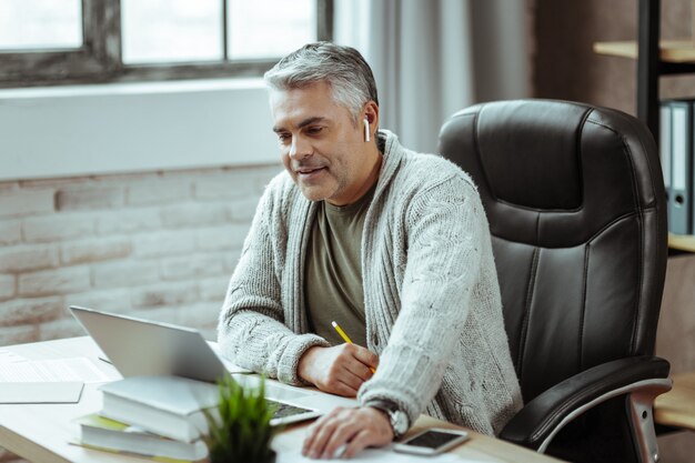 Il mio lavoro. simpatico uomo d'affari intelligente seduto nel suo ufficio mentre si gode il suo lavoro