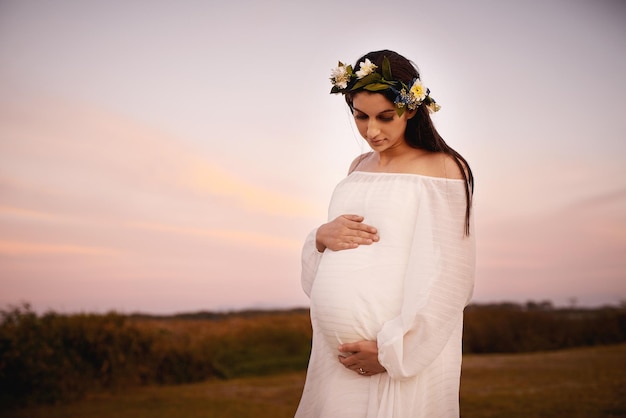 My world in my hands Shot of a young pregnant woman holding her belly outdoors