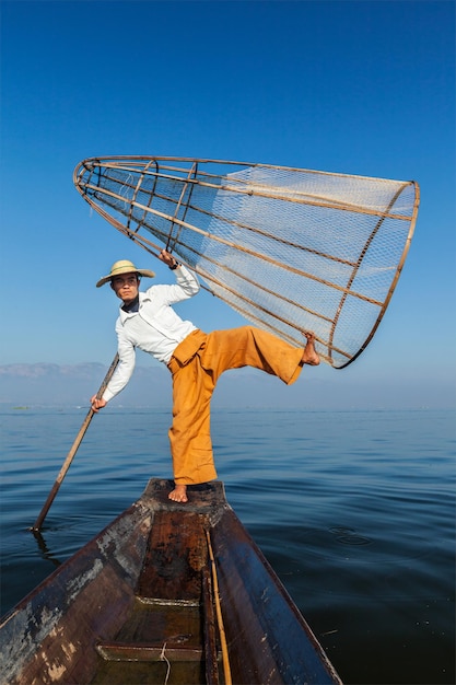 ミャンマー旅行の名所のランドマーク ミャンマーのインレー湖で漁網を持つ伝統的なビルマ漁師は、ボートからの独特の一本足漕ぎスタイルの眺めで有名です