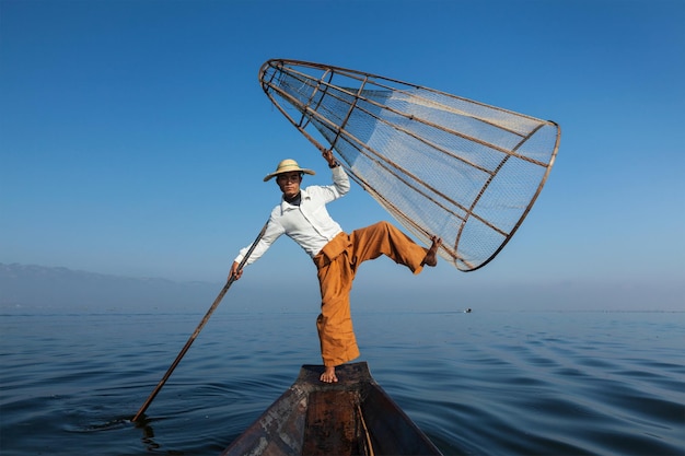Myanmar travel attraction landmark Traditional Burmese fisherman with fishing net at Inle lake in Myanmar famous for their distinctive one legged rowing style
