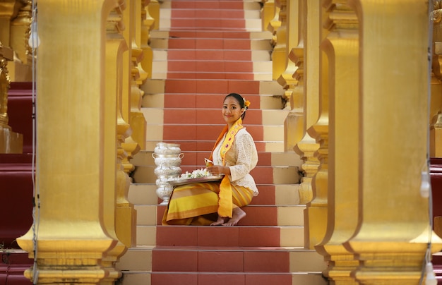 Myanmar women holding flowers at a temple. Southeast Asian young girls with burmese traditional dress visiting a Buddihist temple