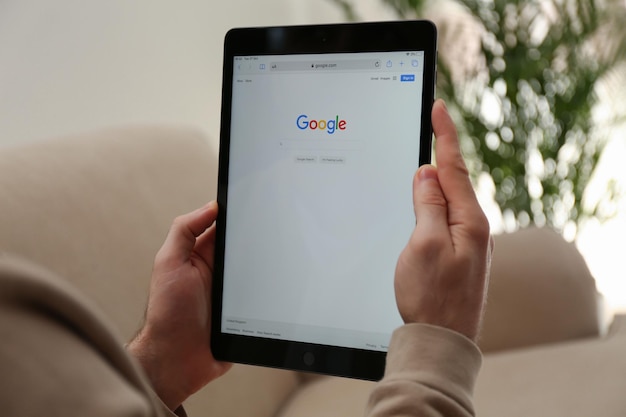 MYKOLAIV UKRAINE 27 OKTOBER 2020 Man gebruikt Google-zoekmachine op tablet tegen onscherpe achtergrond close-up