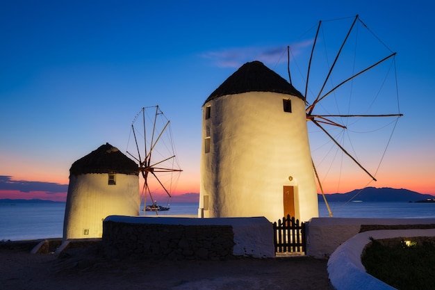 Mykonos Greece Traditional windmills The symbol of Mykonos during sunset Landscape during sunset Sea shore and beach Photo for travel and vacation