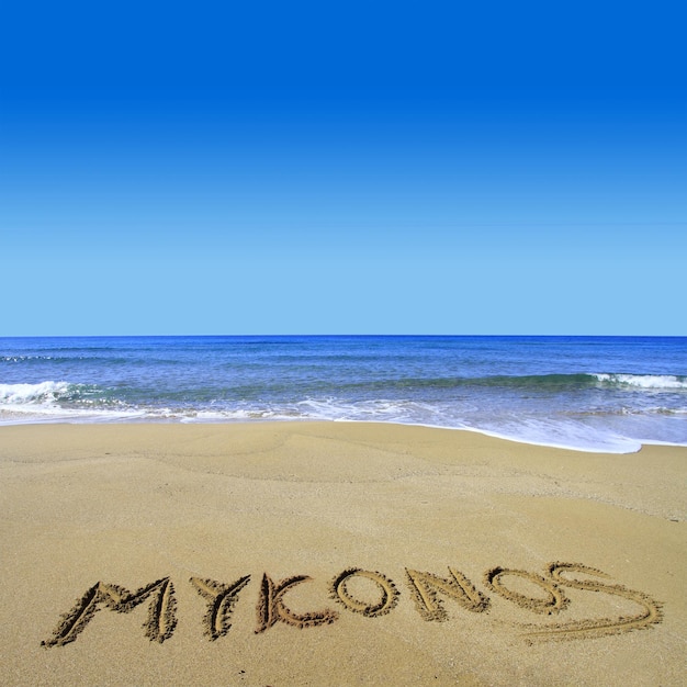 Foto mykonos scritta sulla spiaggia sabbiosa