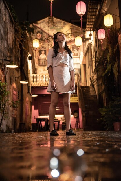 Mysterious asian woman standing next to a crystal ball in the street at night