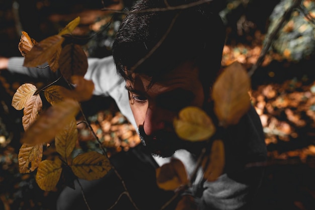 Mysterious man hidden among autumn leaves