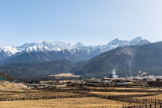 チベット人が住む神秘的な雪に覆われた高原の雪をかぶった山々は、中国のチベット村に住んでいます