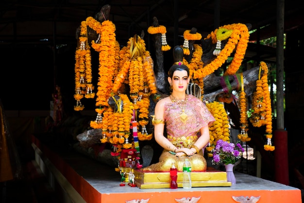 Photo mysterious tree and chao mae takhian thong statue shrine for thai people traveler visit and respect praying blessing wish myth holy worship mystical at wat don khanak temple in nakhon pathom thailand