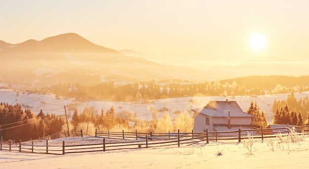 The mysterious winter landscape is majestic mountains in winter. Fantastic sunset. Recording houses in the snow. Photo courtesy postcard. Carpathians