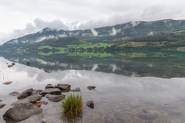 ノルウェーの神秘的なフィヨルドで、山と霧が美しいモノクロブルーの色で水にかかっています。