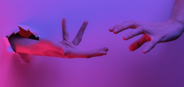 Mystical halloween concept. Hand through a torn hole. Creative pop art pink blue neon color. Trendy gradient illumination. Night light