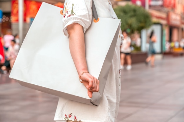Na een dagje winkelen. Close-up van een jonge vrouw die boodschappentassen draagt terwijl ze over straat loopt