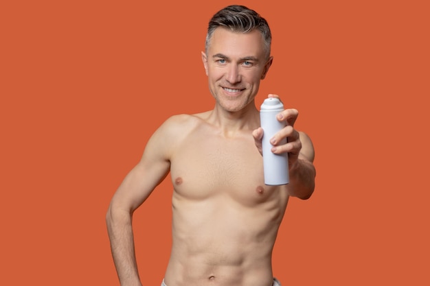 Na het douchen. Een man van middelbare leeftijd met een deospray die er vrolijk uitziet na het douchen